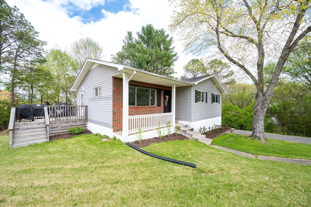 single story home with covered porch, a front yard, and brick siding