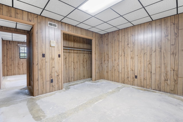 401 Laymons Rd, Hixson, TN 37343 - spare room featuring visible vents, unfinished concrete flooring, a paneled ceiling, and wood walls