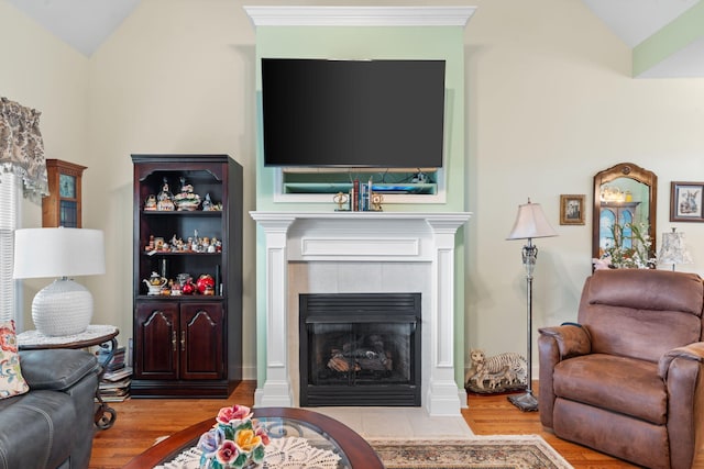 living room with wood finished floors, lofted ceiling, and a tile fireplace