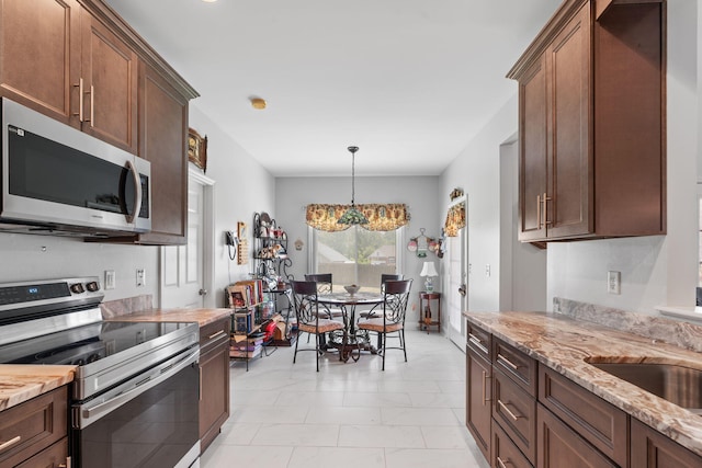 kitchen featuring marble finish floor, light stone counters, a sink, appliances with stainless steel finishes, and hanging light fixtures