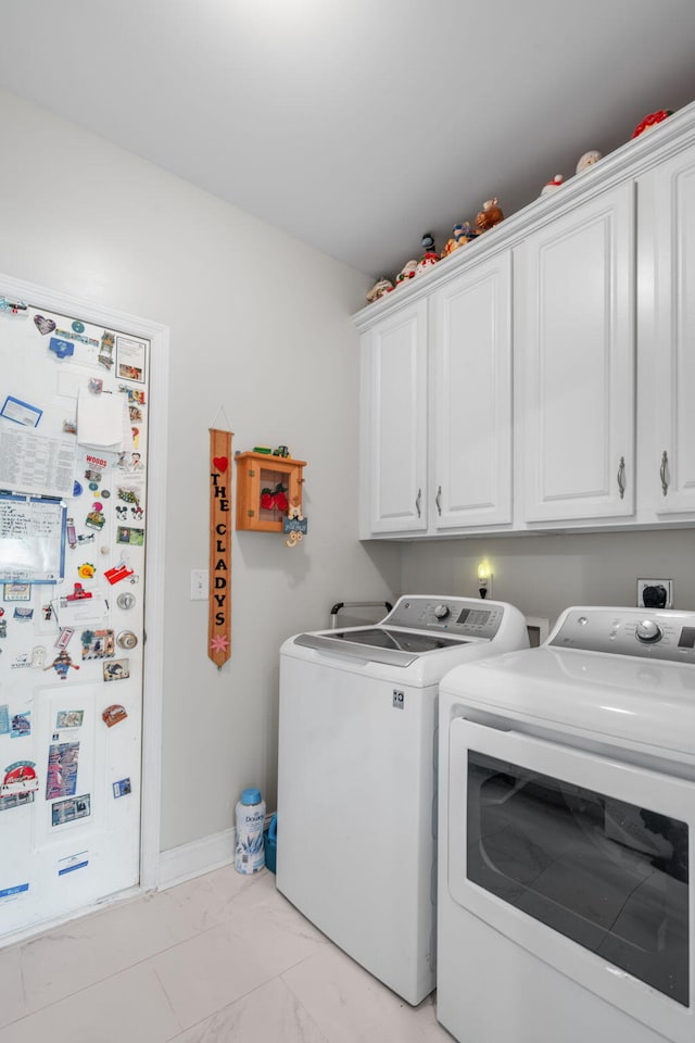 washroom featuring washing machine and dryer, cabinet space, and marble finish floor