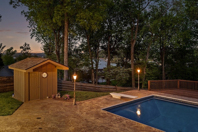 6500 Waconda Point Rd, Harrison, TN 37341 - pool at dusk with a storage unit, fence, a diving board, an outdoor structure, and an outdoor pool