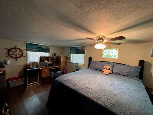 bedroom with a textured ceiling, dark wood-style floors, multiple windows, and ceiling fan