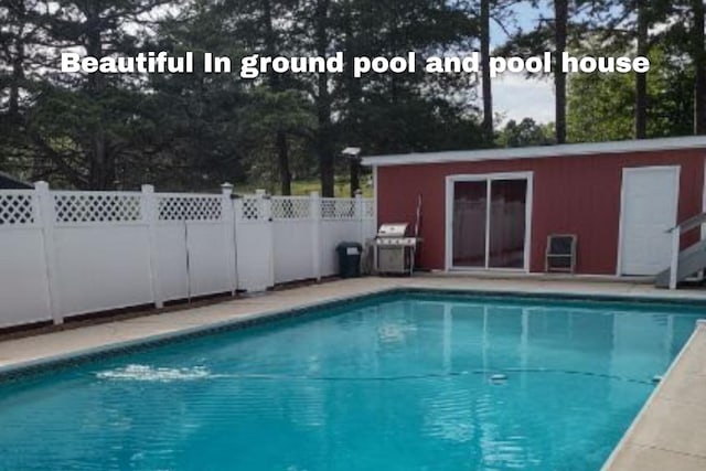 view of swimming pool featuring fence, grilling area, an outbuilding, and a fenced in pool