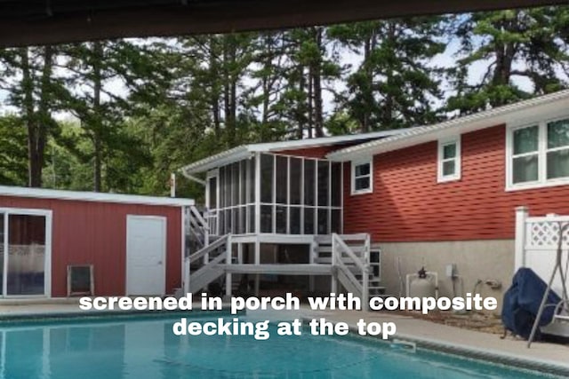 rear view of house featuring an outdoor structure, a sunroom, and an outdoor pool