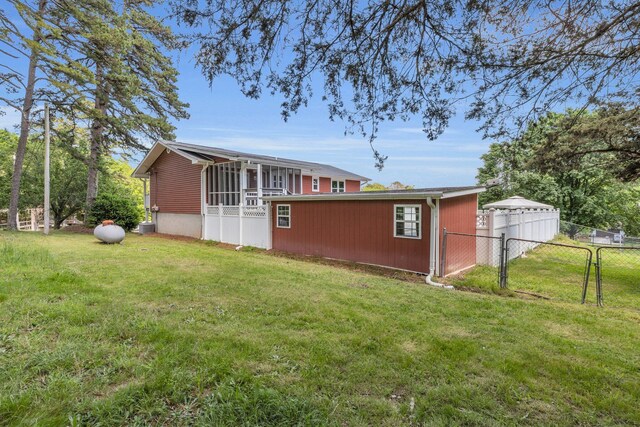 back of house with fence, a gate, a yard, and a sunroom