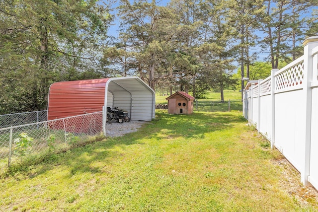 view of yard with an outbuilding, a detached carport, a storage unit, and fence private yard