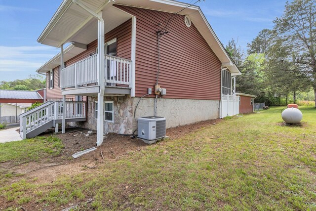 view of property exterior featuring central air condition unit, a yard, and a balcony