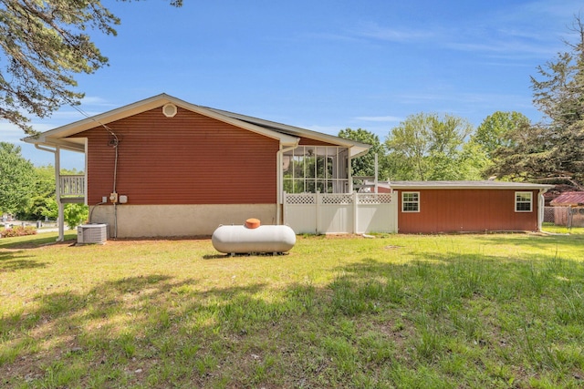 view of property exterior with central air condition unit, a sunroom, and a lawn
