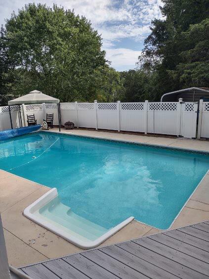 view of swimming pool with a gazebo, a fenced backyard, a wooden deck, and a fenced in pool