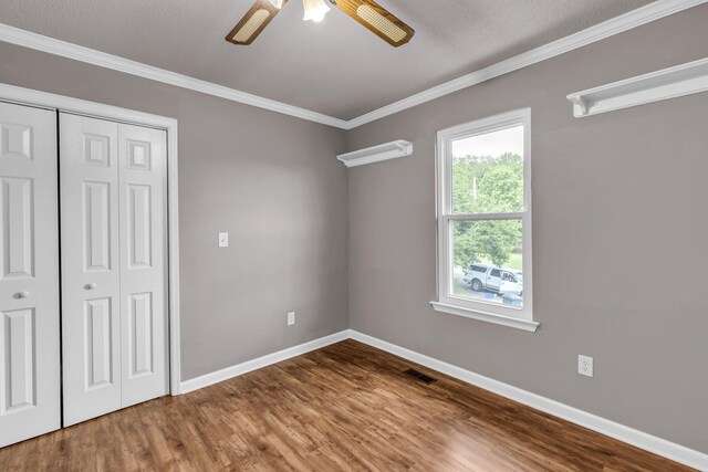 unfurnished bedroom featuring crown molding, visible vents, wood finished floors, and baseboards