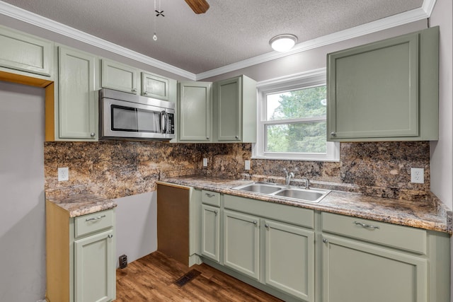 kitchen with a sink, green cabinets, and stainless steel microwave
