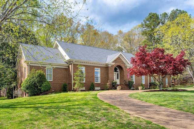 view of front of property featuring brick siding, a front lawn, and a shingled roof