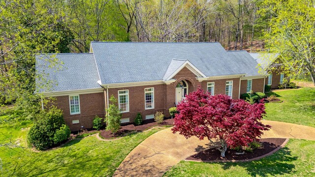 view of front of house featuring a shingled roof, brick siding, crawl space, and a front lawn