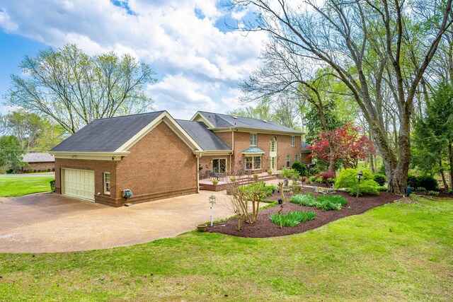 view of front facade with an attached garage, driveway, a front lawn, and brick siding