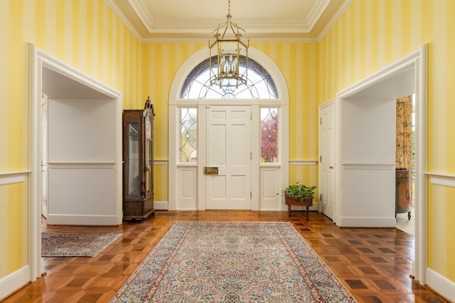 entrance foyer with a notable chandelier, wallpapered walls, crown molding, wainscoting, and a decorative wall