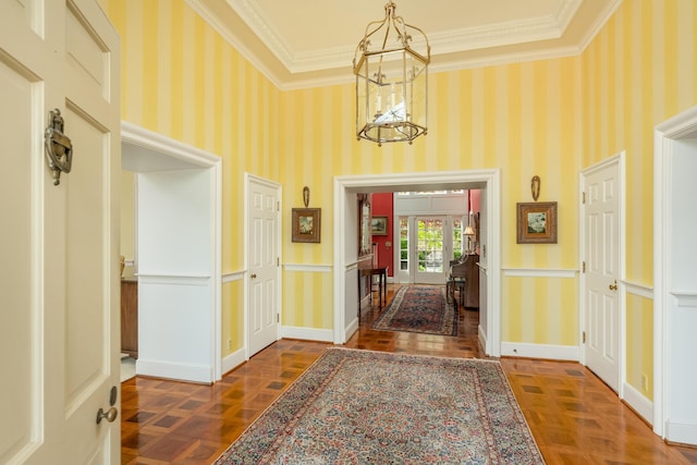 entrance foyer featuring ornamental molding, baseboards, an inviting chandelier, and wallpapered walls