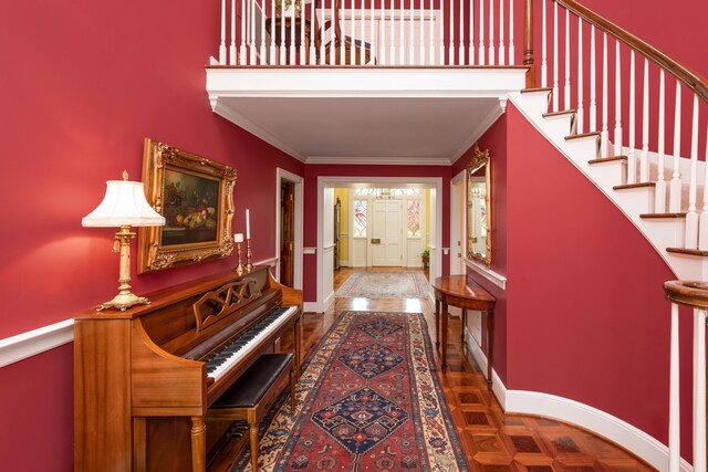 foyer entrance featuring a high ceiling, baseboards, ornamental molding, and stairs