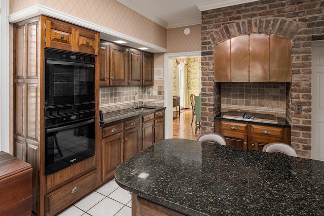 kitchen with crown molding, light tile patterned floors, black appliances, a sink, and decorative backsplash