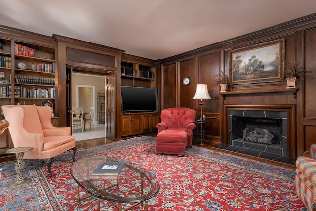 living room with a fireplace with flush hearth, ornamental molding, and built in shelves