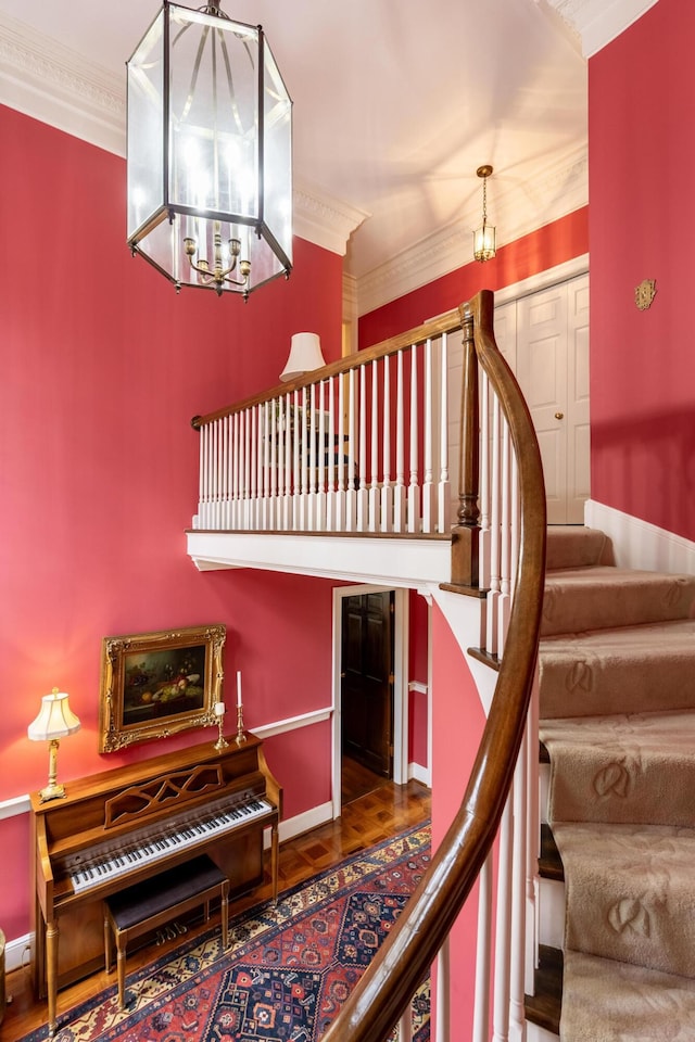 staircase with ornamental molding, baseboards, a notable chandelier, and wood finished floors