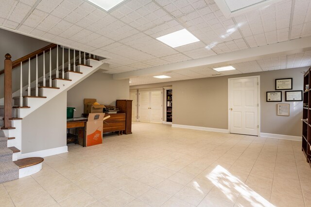 below grade area featuring baseboards, tile patterned flooring, and stairs