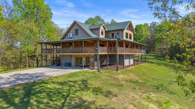 back of property featuring a deck, a garage, a lawn, and concrete driveway