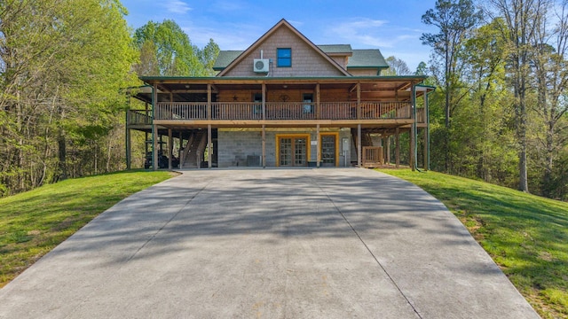 log home featuring a front lawn, a deck, and concrete driveway