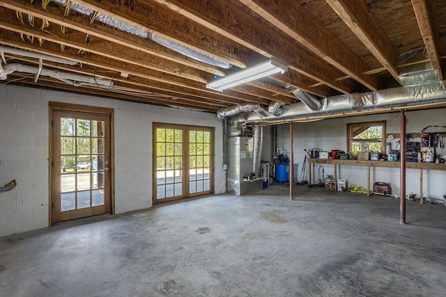 below grade area with french doors, a wealth of natural light, concrete block wall, and heating unit