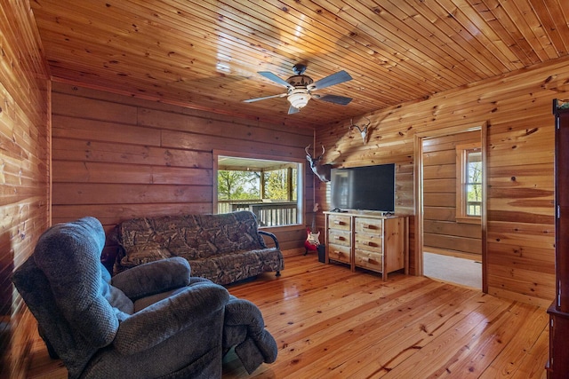 living area featuring hardwood / wood-style floors, wooden walls, ceiling fan, and a wealth of natural light