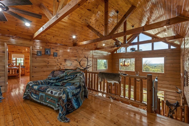 living area with wood walls, high vaulted ceiling, ceiling fan, and beam ceiling