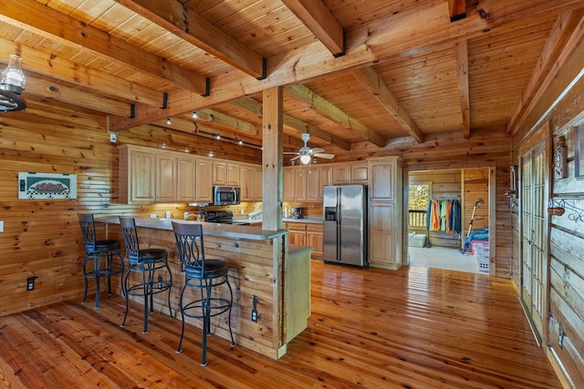 kitchen featuring wooden walls, a peninsula, light wood-style floors, appliances with stainless steel finishes, and wooden ceiling