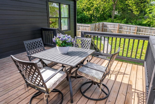 wooden terrace featuring outdoor dining area, a fenced backyard, and a yard