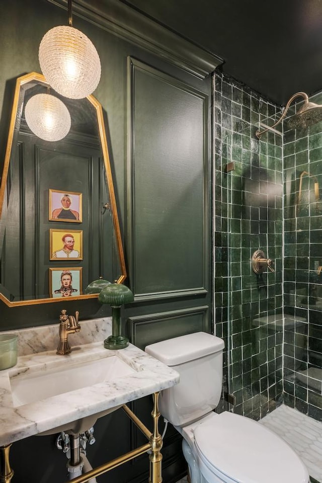 bathroom featuring a sink, toilet, and tiled shower