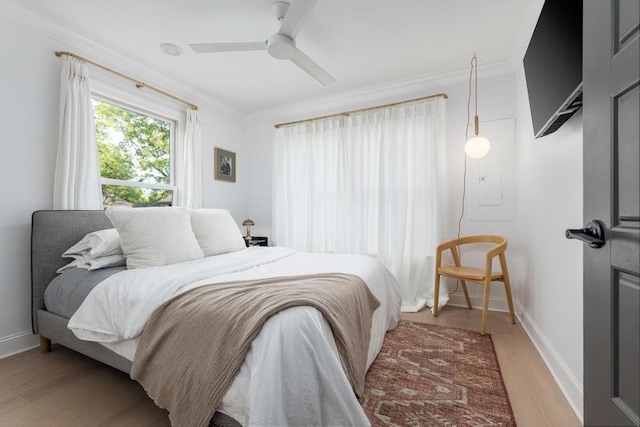 bedroom featuring light wood-style floors, baseboards, ornamental molding, and a ceiling fan
