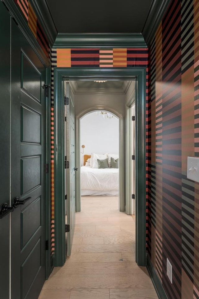 hallway with crown molding, wallpapered walls, and light wood-style flooring