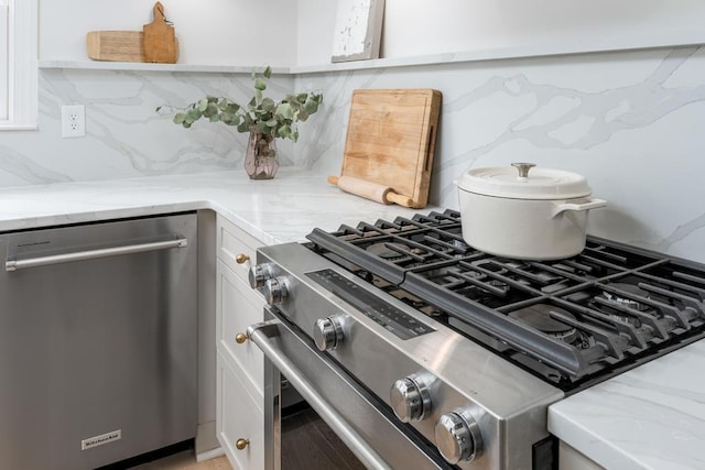room details featuring white cabinets, stainless steel appliances, light stone counters, and tasteful backsplash