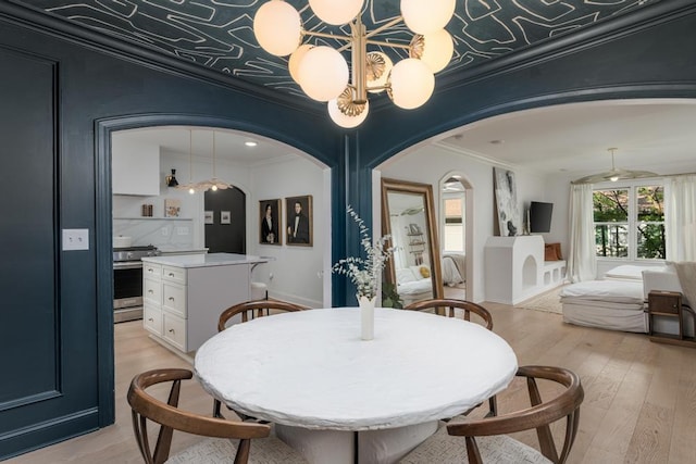 dining space featuring arched walkways, ornamental molding, and light wood finished floors
