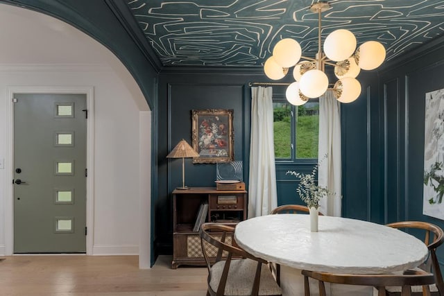 dining space featuring arched walkways, ornamental molding, baseboards, and wood finished floors
