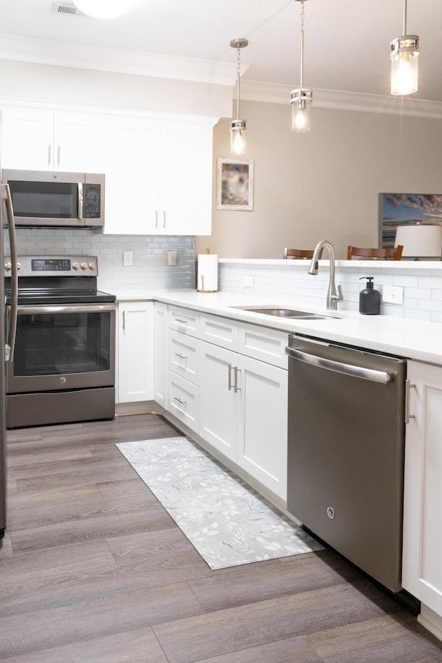 7845 Legacy Park Ct, Chattanooga, TN 37421 - kitchen featuring appliances with stainless steel finishes, crown molding, white cabinetry, decorative backsplash, and light countertops