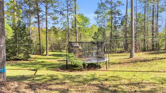 view of yard featuring a wooded view and a trampoline