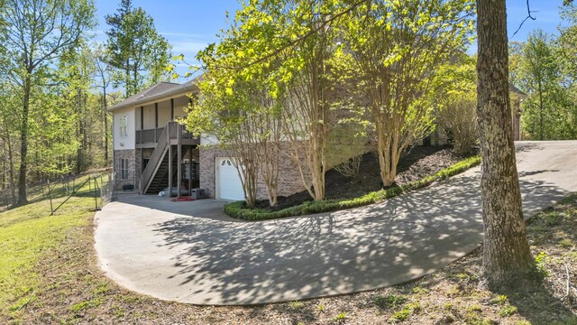 view of front of home featuring a garage, stairs, brick siding, and concrete driveway