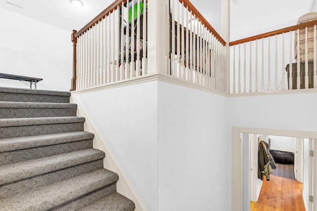 staircase featuring wood finished floors and a towering ceiling
