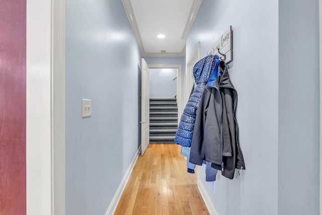 hall featuring crown molding, baseboards, light wood finished floors, and stairway