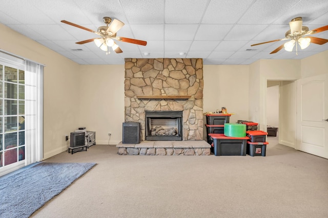 living room with carpet flooring, a fireplace, a ceiling fan, and baseboards
