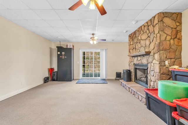 living area featuring carpet floors, a ceiling fan, a paneled ceiling, and a fireplace