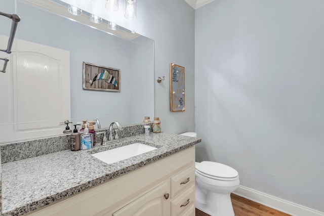 bathroom featuring toilet, vanity, wood finished floors, and baseboards
