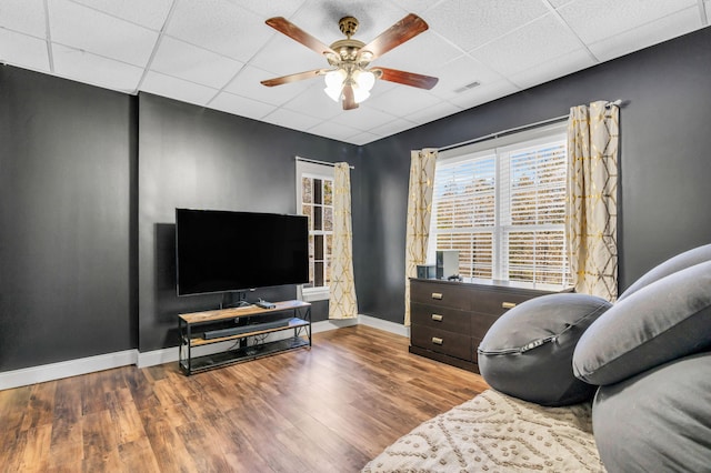 living room featuring a paneled ceiling, baseboards, wood finished floors, and ceiling fan