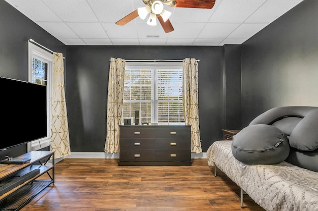 bedroom featuring visible vents, baseboards, a ceiling fan, wood finished floors, and a drop ceiling