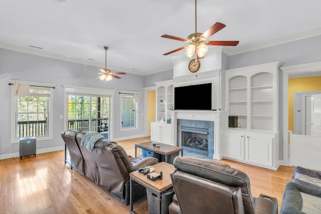 living area featuring light wood-style floors, a tile fireplace, ceiling fan, and baseboards